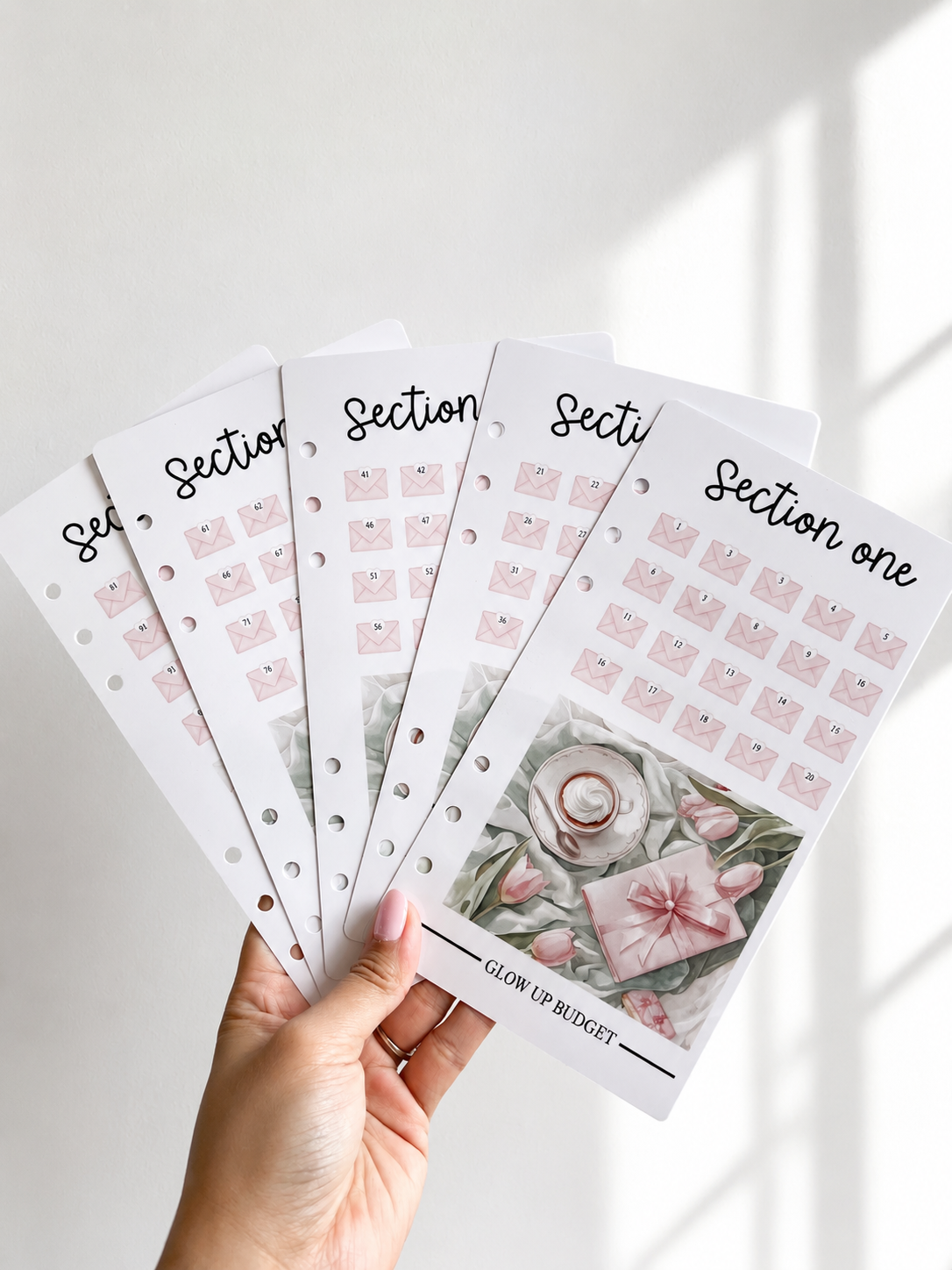 Hand holding savings trackers with floral designs on a light background